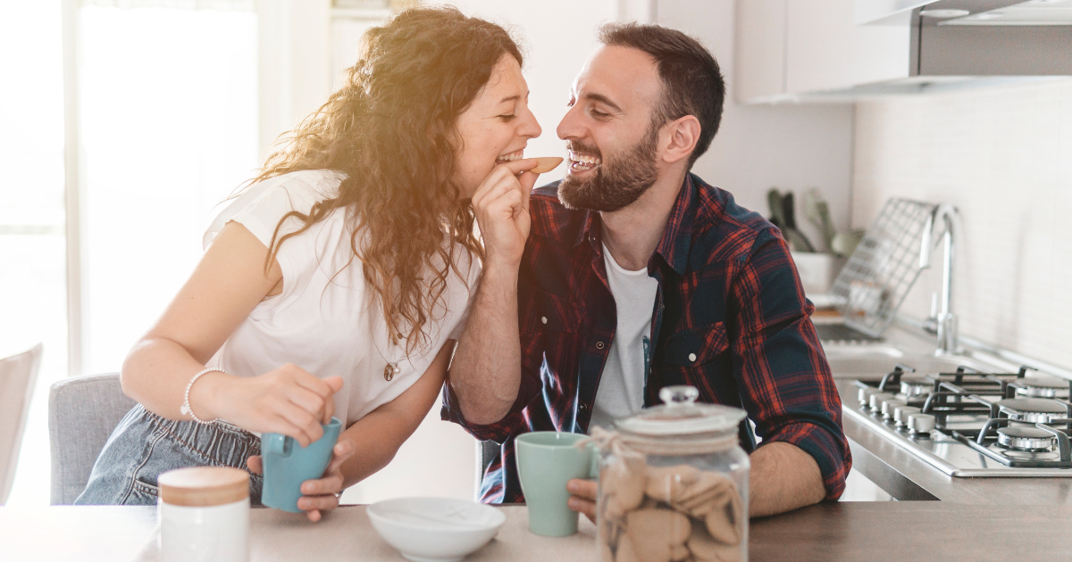 Couple sharing a heart-shaped cookie in the kitchen - applying relationship techniques together
